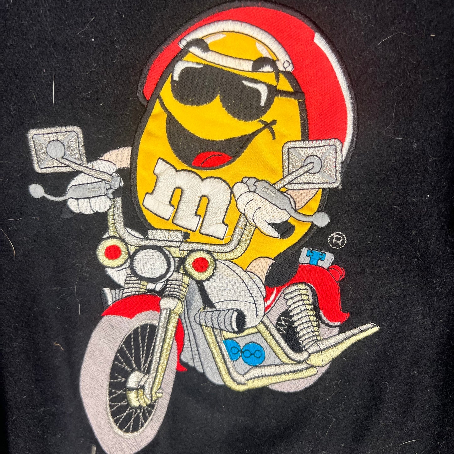 Detailed shot of Yellow M&M embroidery riding motorcycle