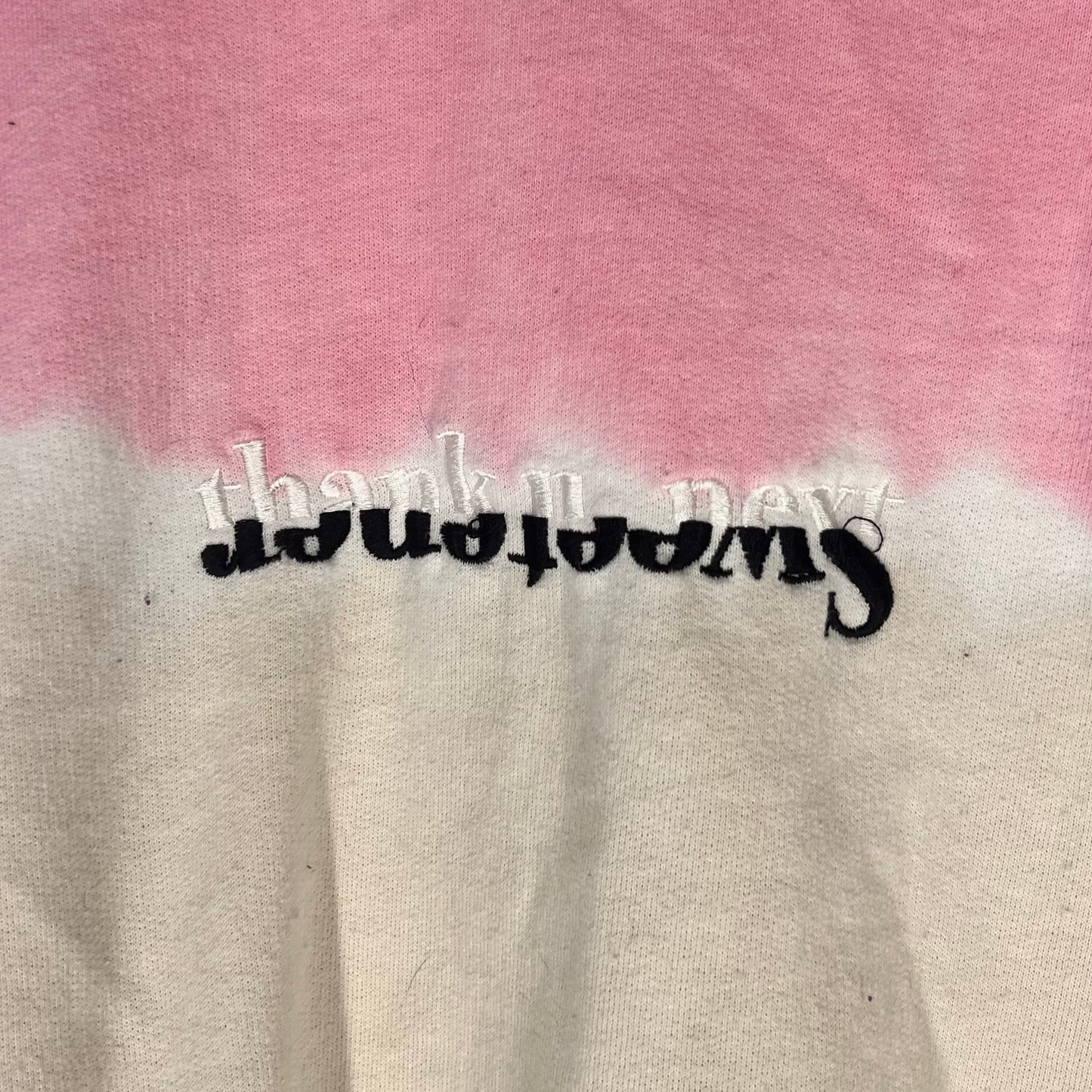 Close-up of upside-down embroidered “Sweetener” with layered “thank u, next” detail