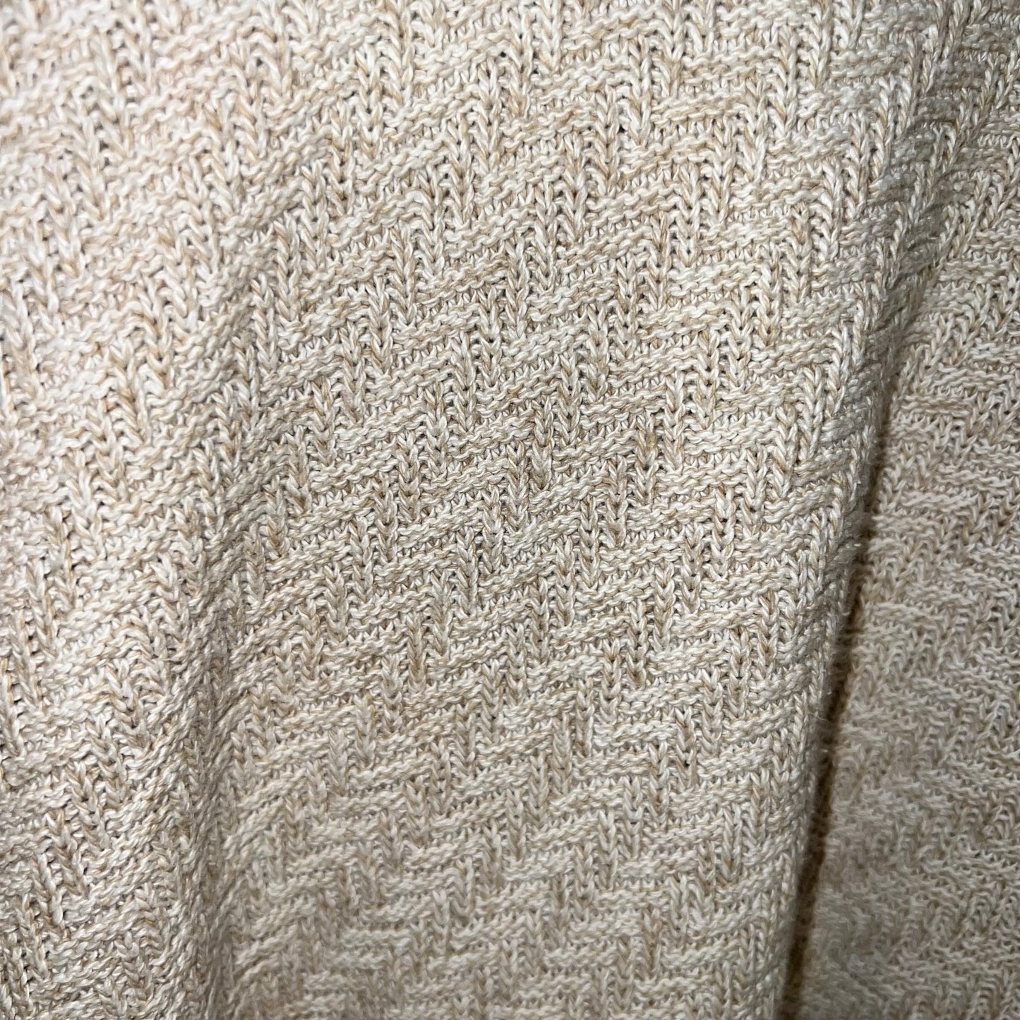 lose-up of herringbone knit pattern texture in oatmeal/tan yarn