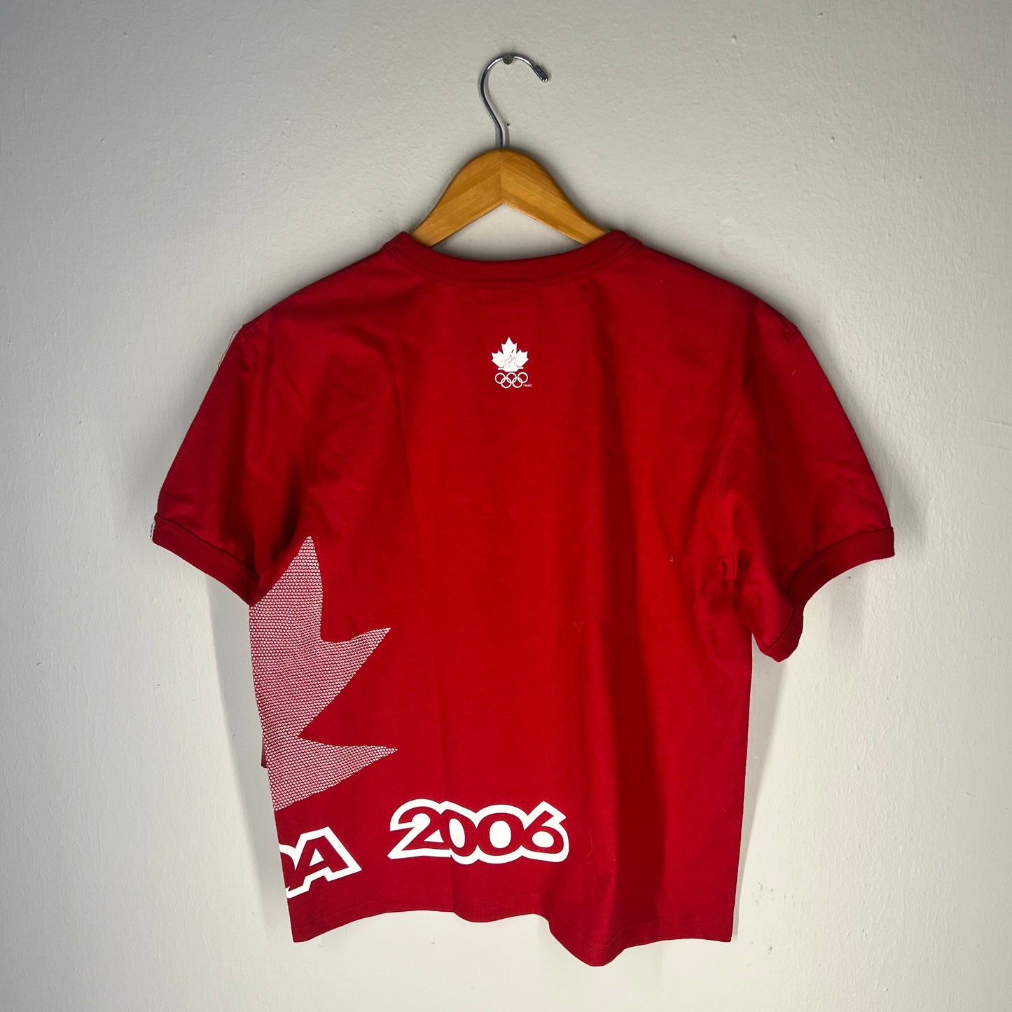 Back view of tee with maple leaf wrap graphic, “2006” print, and Olympic logo under neckline.
