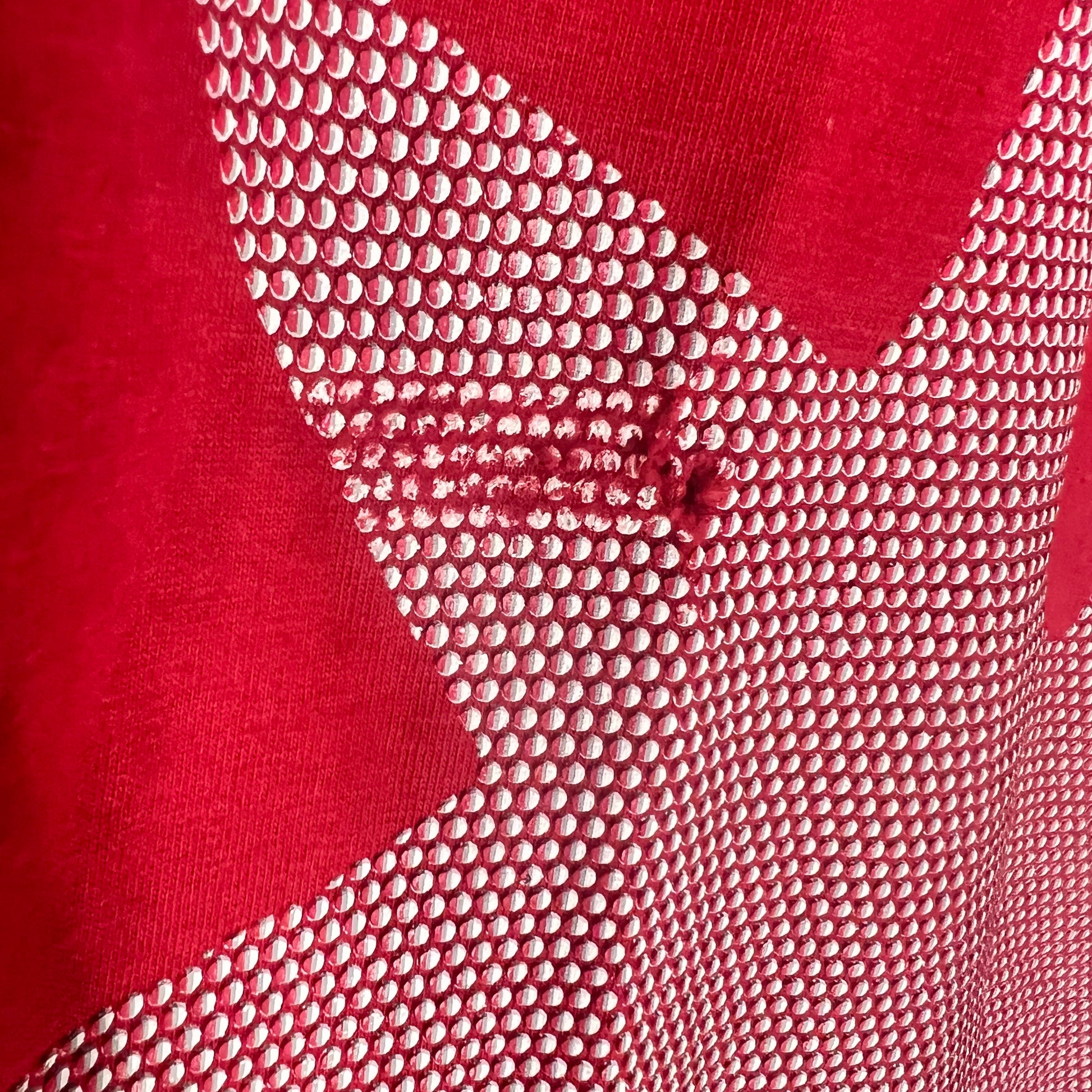 Close-up of halftone maple leaf print and Canada text detail on front.