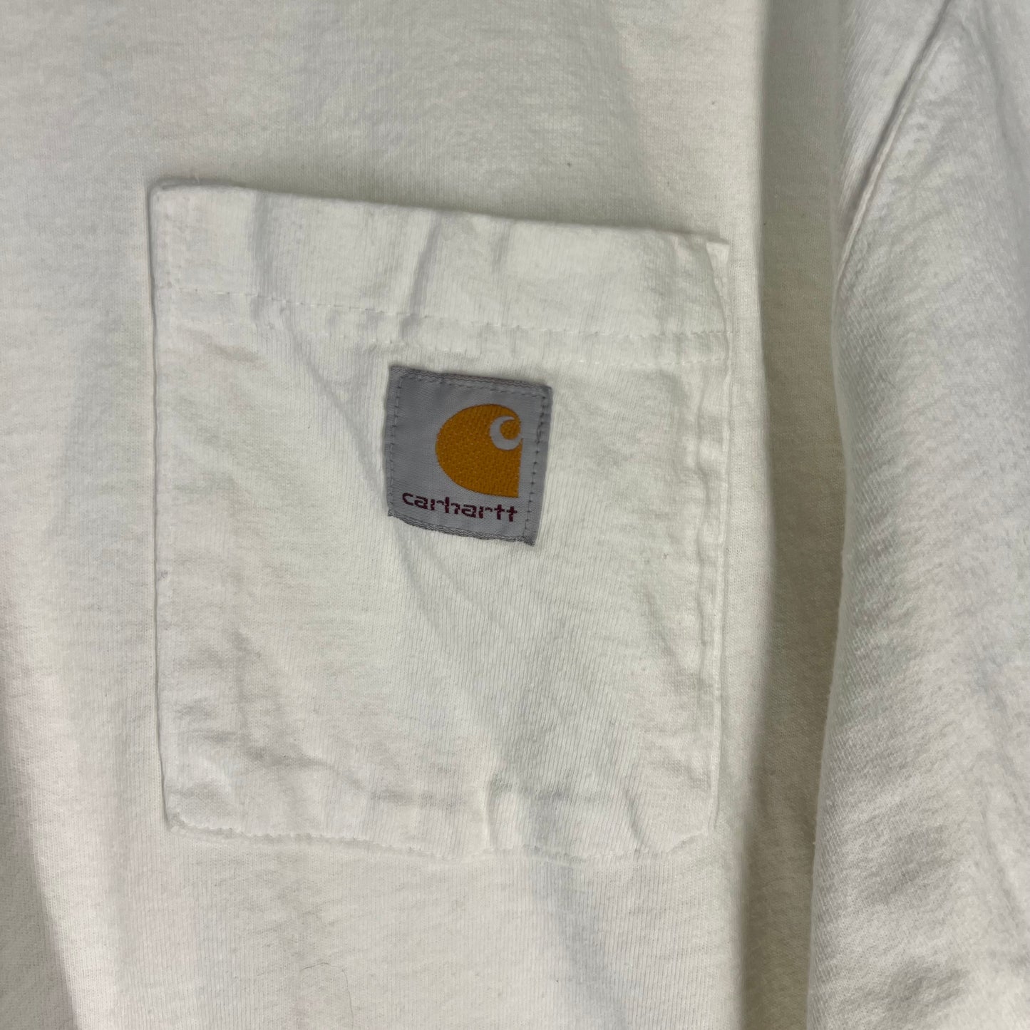 Close-up of Carhartt logo patch on pocket of white T-shirt