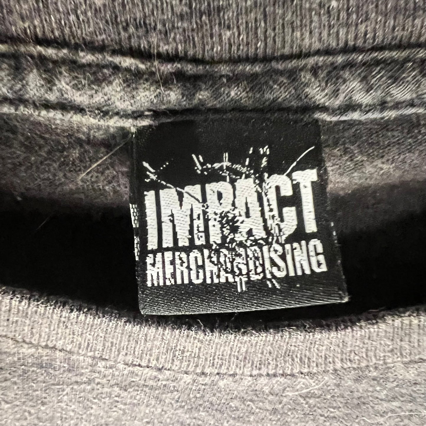 Tag close-up of Impact Merchandising logo on inside collar of tee