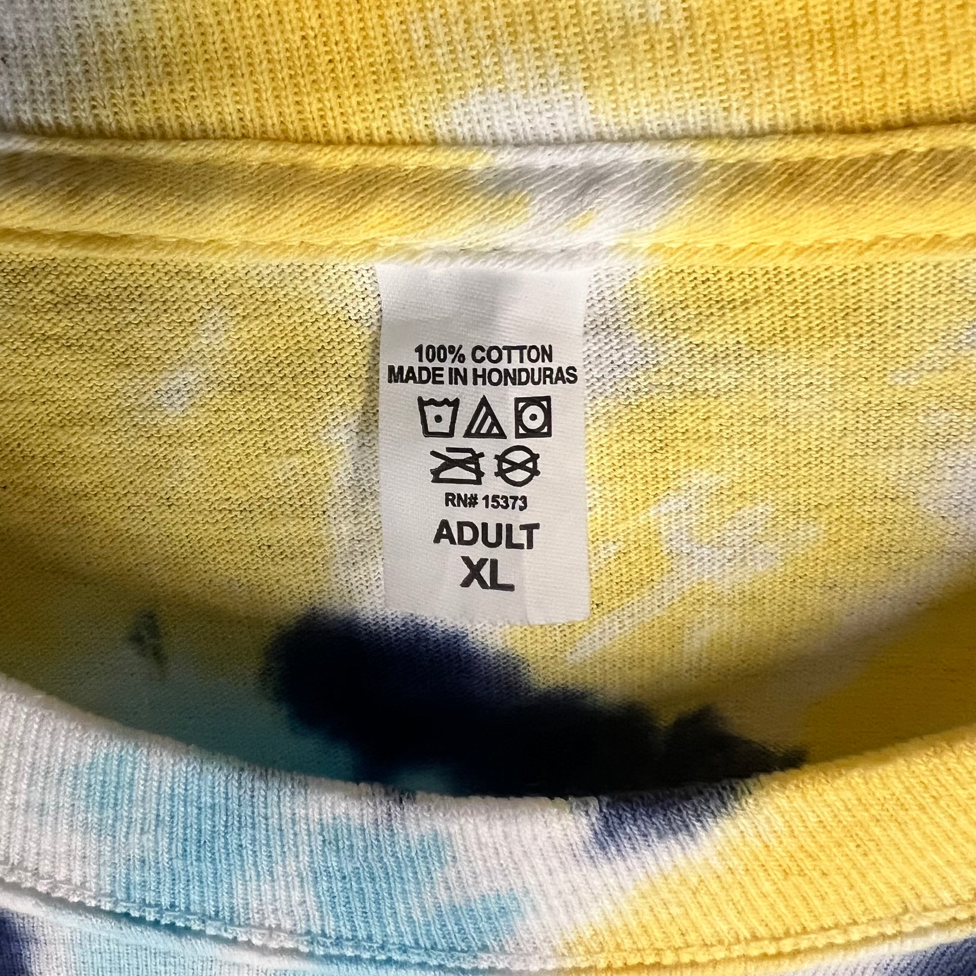 Neck tag close-up on Grateful Dead tie-dye shirt reading 100% cotton made in Honduras XL