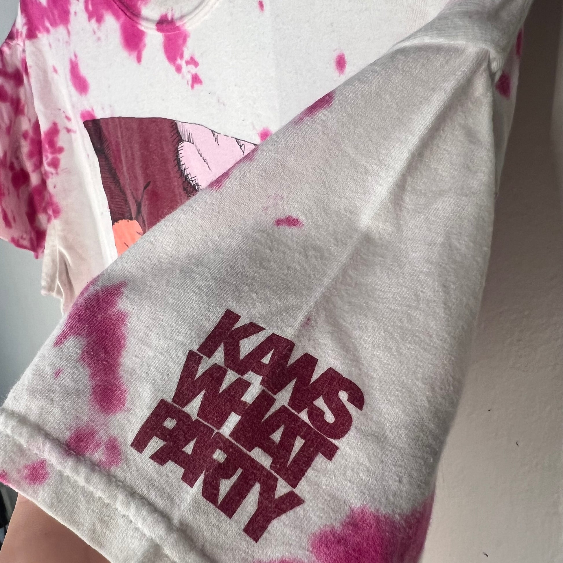 Sleeve detail showing ‘KAWS WHAT PARTY’ print on tie‑dye tee